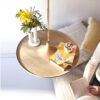Table suspendue en bois de chêne avec tige en laiton, placée dans un salon, avec des fleurs disposée dessus